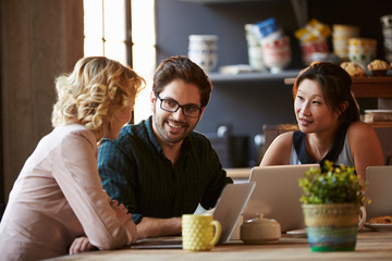 Three Businesspeople Working At Laptop In cafe