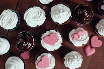 a lot of cupcakes with pink little candy hearts on topping.top v