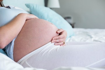 Pregnant woman sitting on bed 