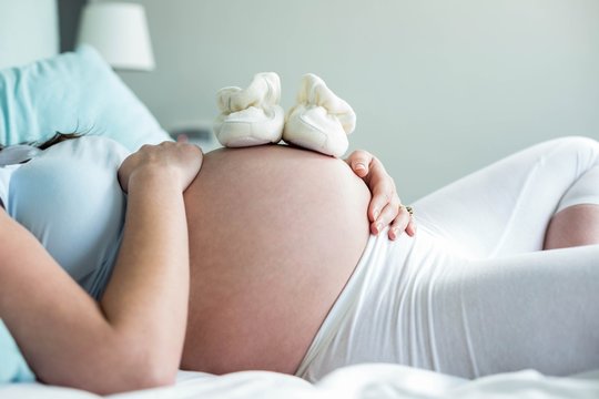 Pregnant Woman With Baby Shoes On Belly