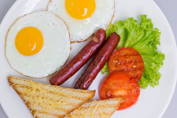 English breakfast with fried eggs, sausages, toasts and fresh salad, top view