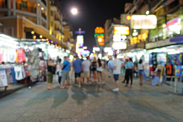 Naklejka na ściany i meble Travelers stands at night market in blur mode