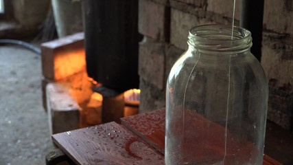 Final stage of illegal hooch alcohol production in rural farm room. Strong drink liquid flow in glass jar. Static closeup shot. 4K
