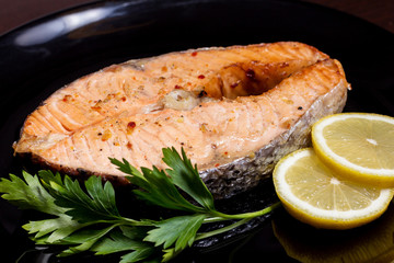 Grilled salmon steak on a black plate