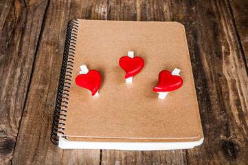 Notepad and hearts on grunge wooden background