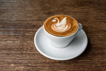 Foto op Aluminium coffee with latte art in swan shape on wooden table © eriyalim