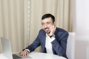 Naklejka premium Portrait of a man with a laptop. A man sits at a Desk and working. 