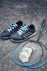 Sport shoes with shuttlecocks and badminton racket.