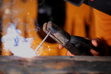 Close-up worker with protective mask welding metal.