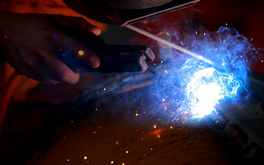 Close-up worker with protective mask welding metal.