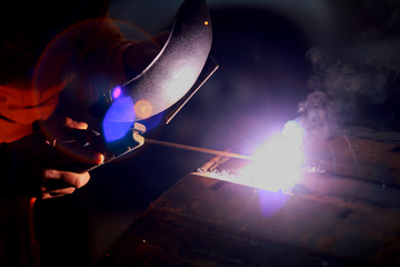 Close-up worker with protective mask welding metal.