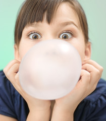 Little girl is blowing big bubble gum