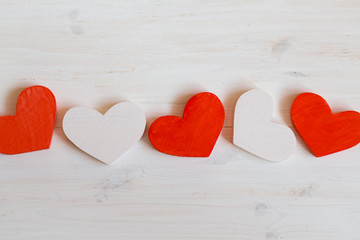 Red and white hearts on white wooden background