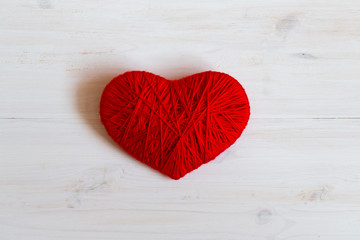 Fototapeta na wymiar Red heart shape made from wool on white wooden background