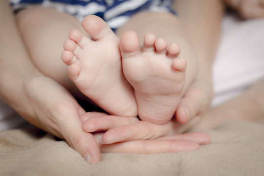 Gentle touch. Woman holding tiny baby feet in her hands