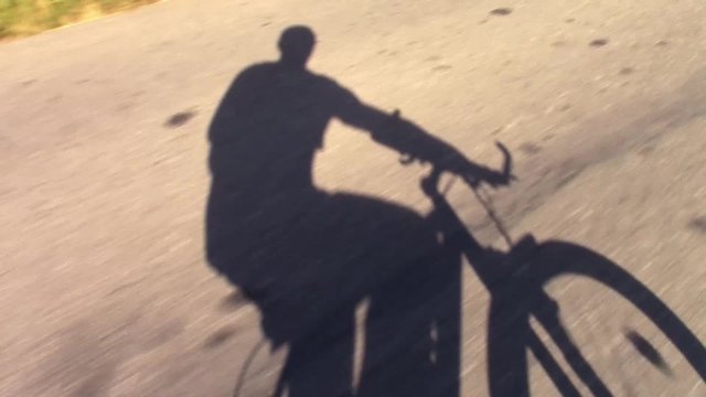 Elongated shadow projection on the road of a person cycling at sunset