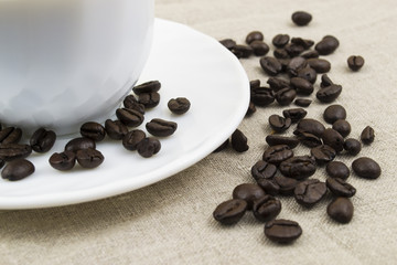 A cup of coffee and coffee beans on a saucer
