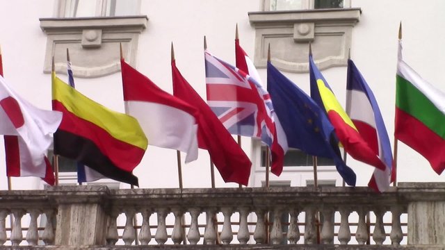 International flags of several countries waving in the wind on the balcony of a building hosting an official meeting