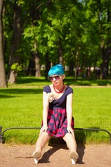 Pinup young woman witch blue hair in vintage style clothing in city park
