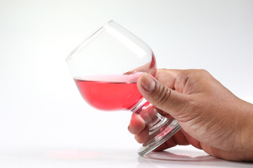Hand holding a glass of red wine on a white background.