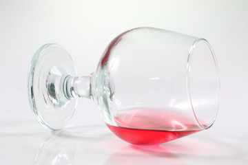 A wineglass with red water in white background.