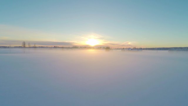 Flying over foggy snow fields in the sunset