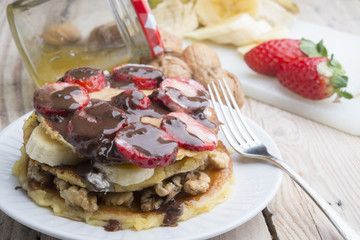 delicious pancakes with nuts, banana, strawberry and chocolate