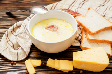 
cheese soup with smoked pork ribs , potatoes, carrots , peppers , spices and bread on the wooden background