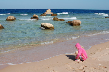 Fototapeta na wymiar Little girl draws a heart on the shore of the Red Sea in Egypt