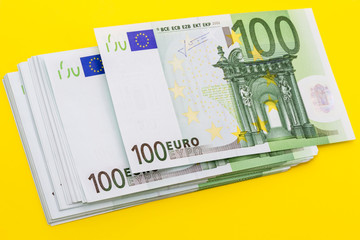 Stack of 100 euro banknotes on a yellow