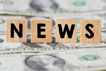 Wooden letters spelling news on money background