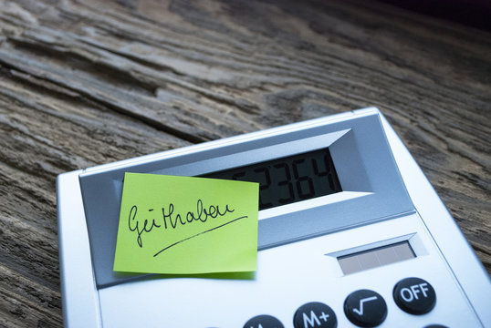 Taschenrechner mit Post it "Guthaben" auf Holz / Treibholz Hintergrund 