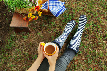 Fototapeta premium Young woman with cup of coffee sitting on meadow outdoors