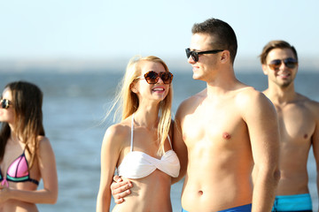 Fototapeta premium Happy couple and their playful friends relaxing at the beach, outdoors