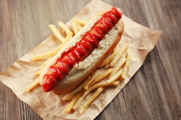 Hot dog with fried potatoes on craft paper