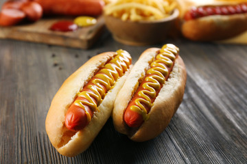 Hot dogs with fried potatoes and fresh sausages on wooden background