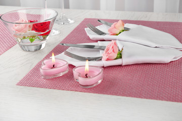 Serving in a napkin with spoon and fork for two person on pink background