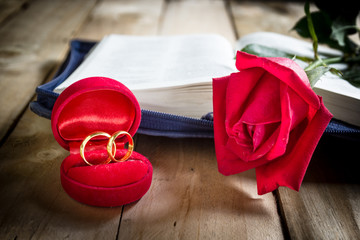 Red roses and wedding rings  on wooden background