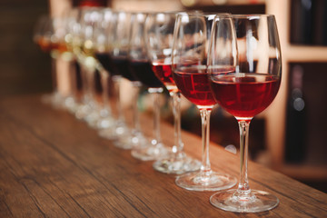 Many glasses of different wine in a row on bar counter
