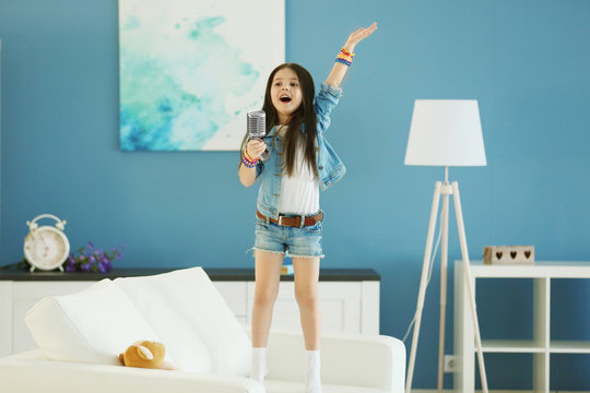 Artistic little girl singing in the room