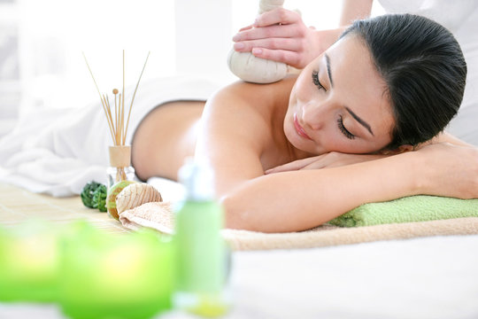 Spa concept. Someone do relaxing massage with herbal balls to beautiful woman, close up