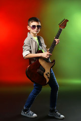 Fototapeta premium Little boy playing guitar on a bright background