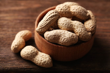 Peanuts in the wooden bowl on the table, close-up