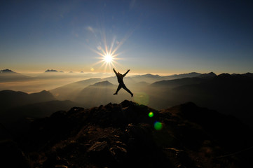 Springender Sportler am Berg bei Sonnenaufgang