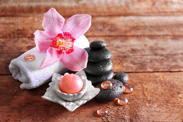 Fototapeta na wymiar Spa stones with pink orchid, candle and towel on wooden background