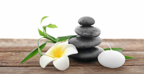 Spa stones with candle, bamboo and tropical flower on white background