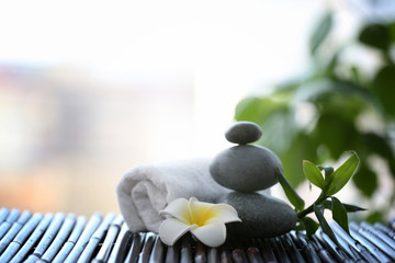 Spa stones with towel and tropical flower on blurred background