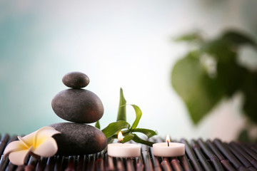 Spa stones with candles and tropical flower on blurred background