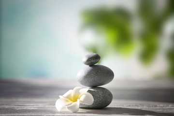 Spa stones with tropical flower on blurred background