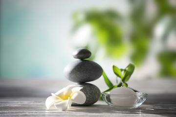 Obraz na płótnie Canvas Spa stones with tropical flower, bamboo and candle on blurred background